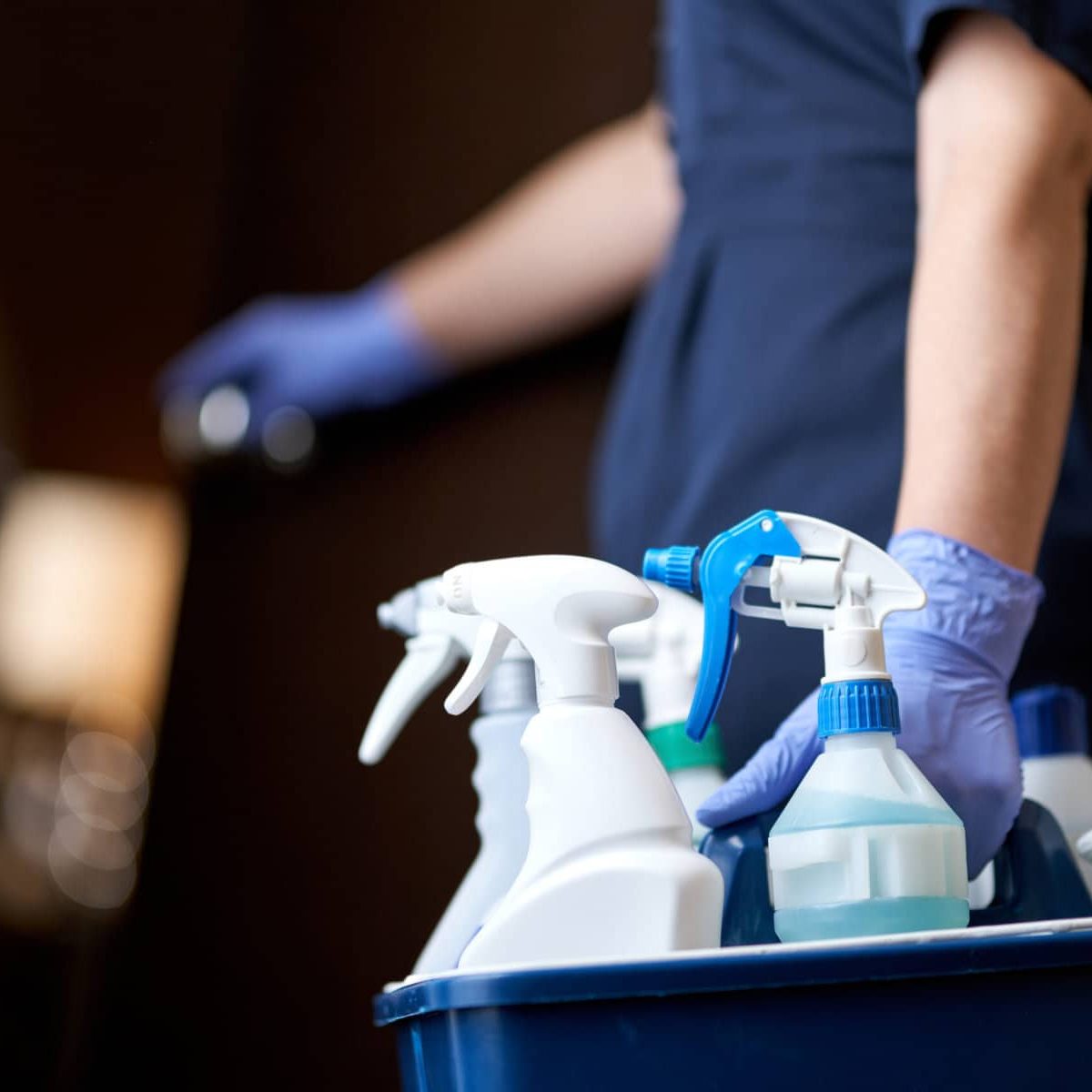 Cropped photo of chambermaid keeping all necessary cleaning and disinfection accessories in hotel room. Hotel service concept
